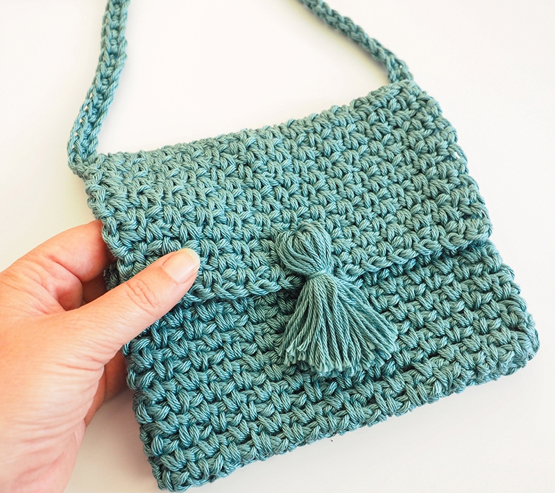 The Cute Cross Body Bag is the perfect size for all the essentials, and it’s far more convenient to carry than larger totes and bags. #crochetbag #crochetpattern #crochetlove #crochetaddict