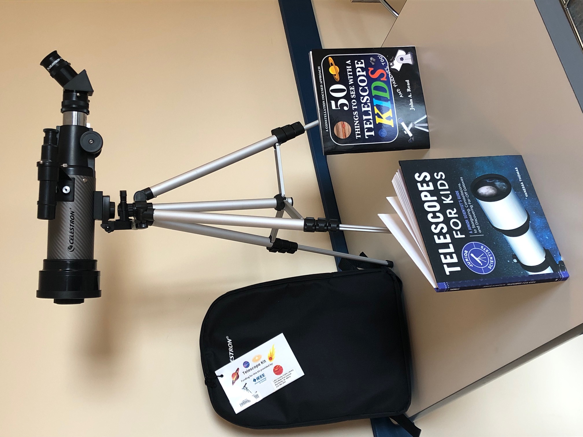 A telescope with a backpack and two kids' books on how to use telescopes A telescope with a backpack and two kids' books on how to use telescopes