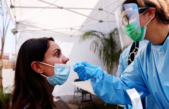 Nightly 7-20-21 photo A registered nurse administers a Covid-19 test to a person at Sameday Testing in Los Angeles.