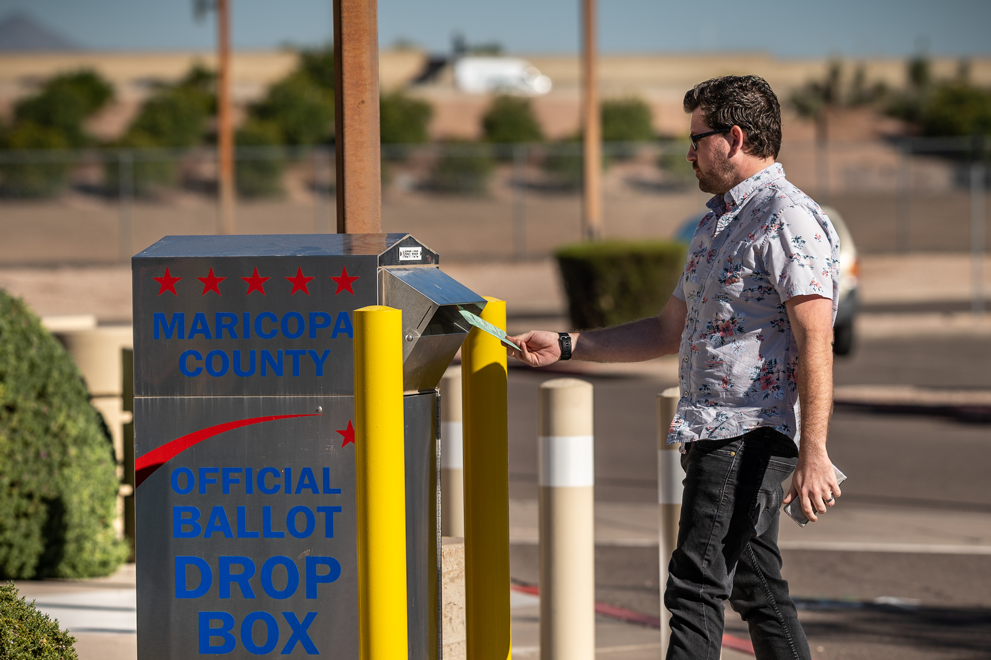 A voter dropping their ballot into a Maricopa County drop box.