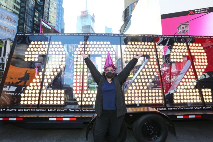 Nightly 12-23-21 photo A person wearing festive new year's hat and glasses poses at the 2022 New Year's Eve numerals as they arrive in Times Square in New York City.