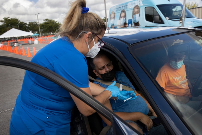 Nightly 12-16-21 photo  A health care worker administers a Pfizer-BioNTech Covid-19 vaccine to a person at a drive-thru site in Tropical Park in Miami.