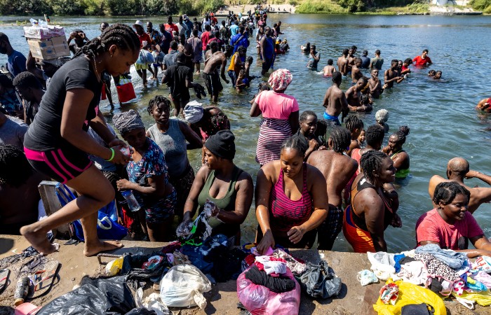 nightly-del-rio-700 Migrants wash their clothes in the Rio Grande River near a makeshift encampment under the International Bridge between Del Rio, Texas and Acuña, Mexico.