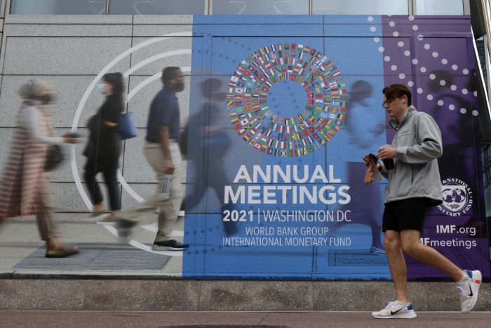 Nightly 10-12-21 photo 2 A man passes by a poster of the annual World Bank Group and International Monetary Fund meetings in Washington.