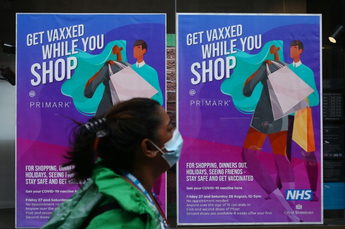 Nightly 10-19-21 photo 3 A pedestrian walks past a poster advertising in-store vaccinations at Primark on Oxford Street in London.