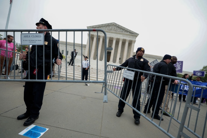 Police officers set up barricades on the sidewalk as pro-abortion rights and anti-abortion activists demonstrate in front of the U.S. Supreme Court building.