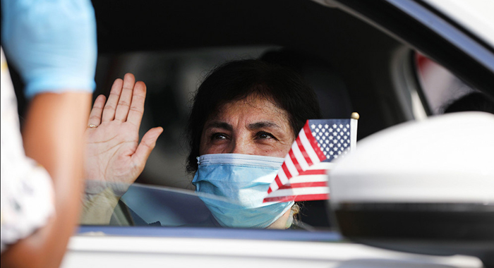 A new U.S. citizen sits in a vehicle while being sworn in by an immigration service officer at a drive-in naturalization ceremony amid the COVID-19 pandemic on July 29, 2020 in Santa Ana, California.