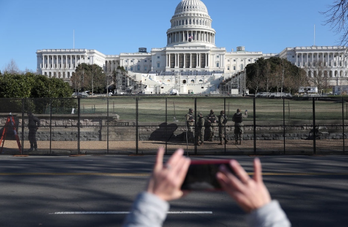 Members of the D.C. National Guard are seen outside the U.S. Capitol Building as workers construct a fence. 