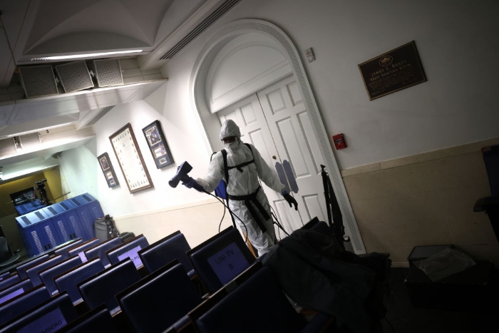 A member of the White House cleaning staff sanitizes the James S. Brady Press Briefing Room.