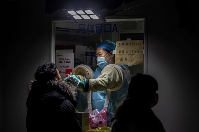Nightly 1-13-22 photo 2 A man is given a nucleic acid test for Covid-19 by a health worker at a private testing site in Beijing.