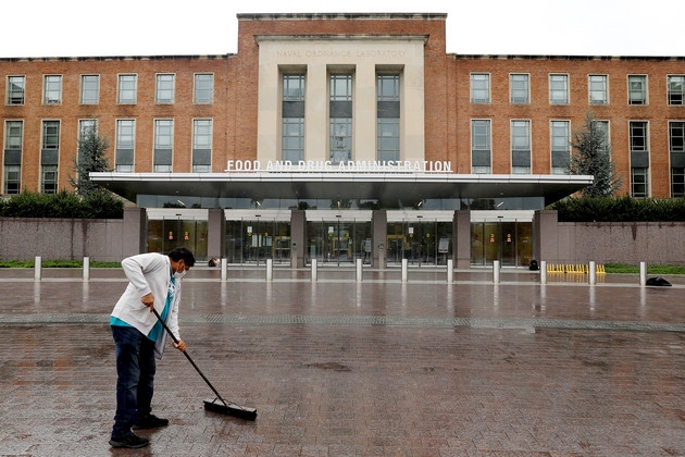 A worker sweeps outside of the Food and Drug Administration headquarters in White Oak, Md.