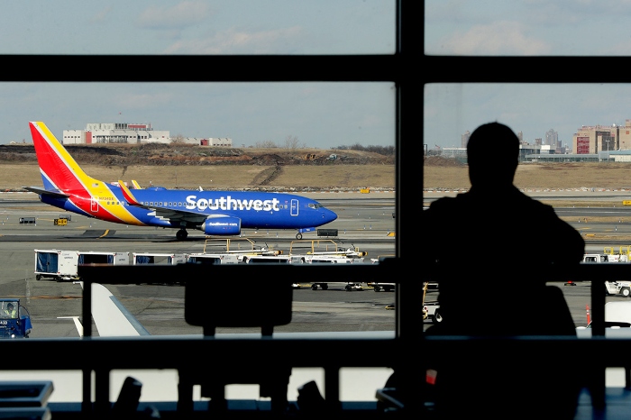 Nightly 10-12-21 photo A Southwest Airlines jet moves on the runway as a person eats at a terminal restaurant at LaGuardia Airport in New York.