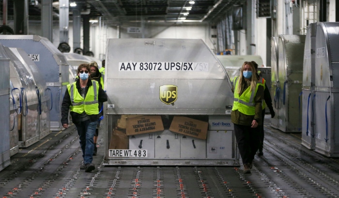 UPS employees move one of two shipping containers containing the first shipments of the Pfizer and BioNTech Covid-19 vaccine inside a sorting facility at UPS Worldport in Louisville, Ky.