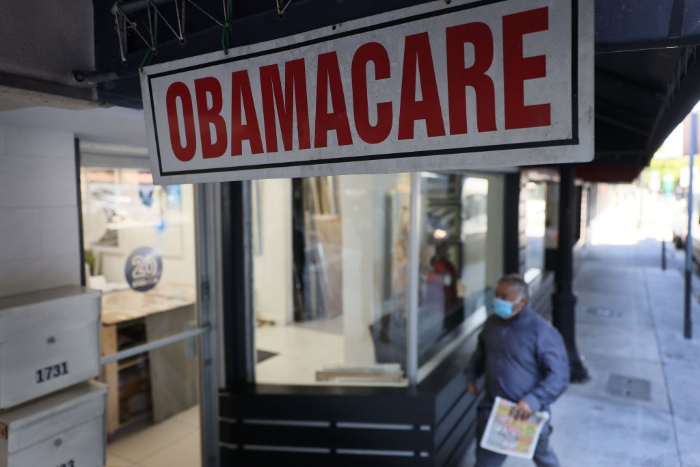 Nightly 7-19-21 photo A pedestrian walks past the Leading Insurance Agency, which offers plans under the Affordable Care Act, in Miami.