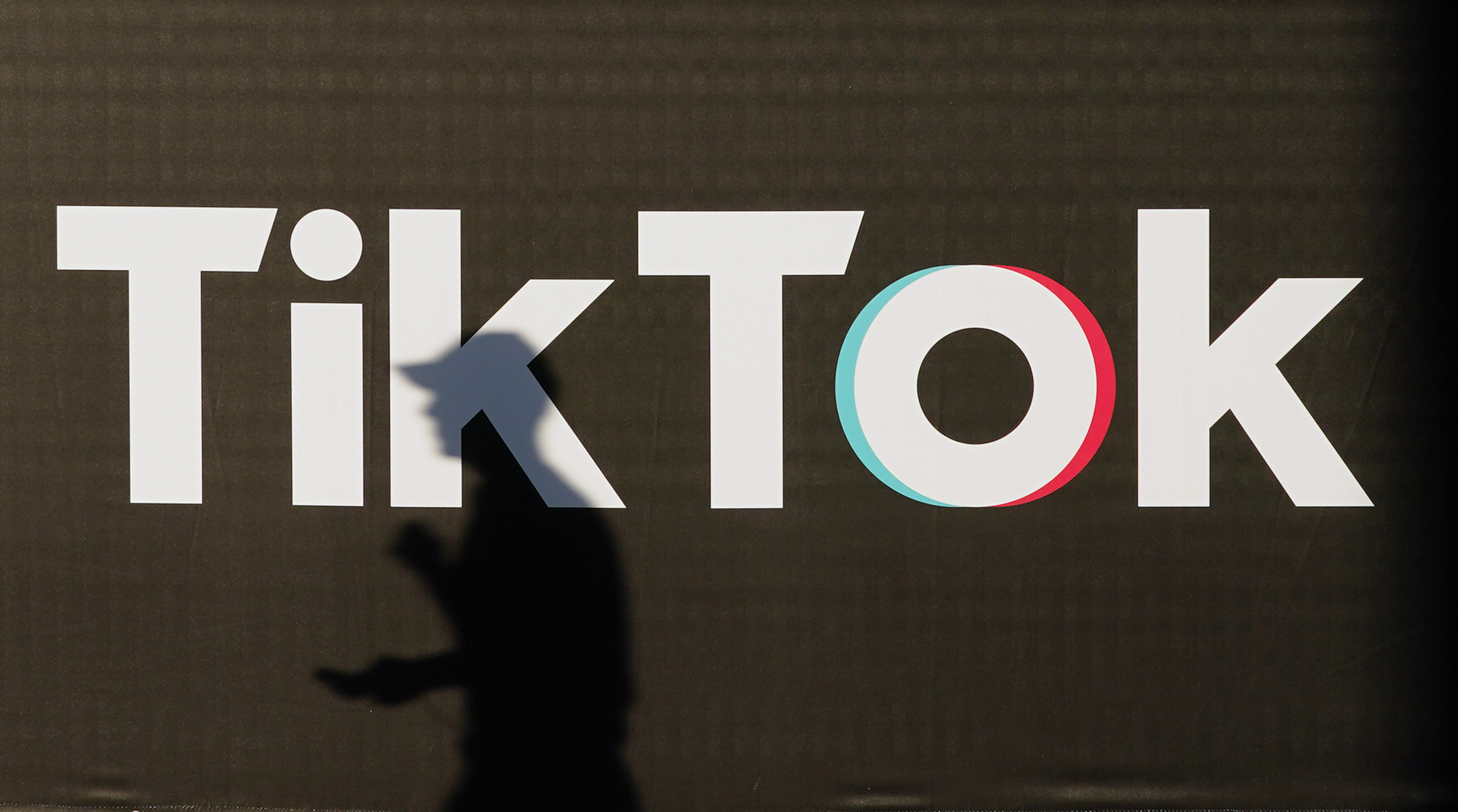 A photo of a shadow in front of a TikTok sign.