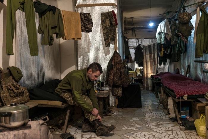 Nightly 1-7-22 photo 2 A Ukrainian soldier puts on his boots in a building on the front line in Marinka, Ukraine.