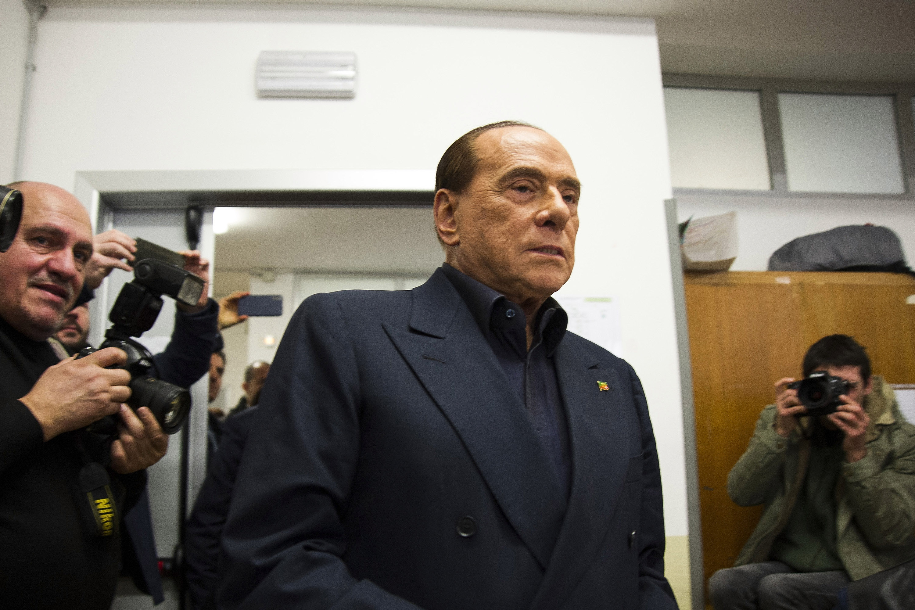 A photo of Silvio Berlusconi surrounded by reporters. 