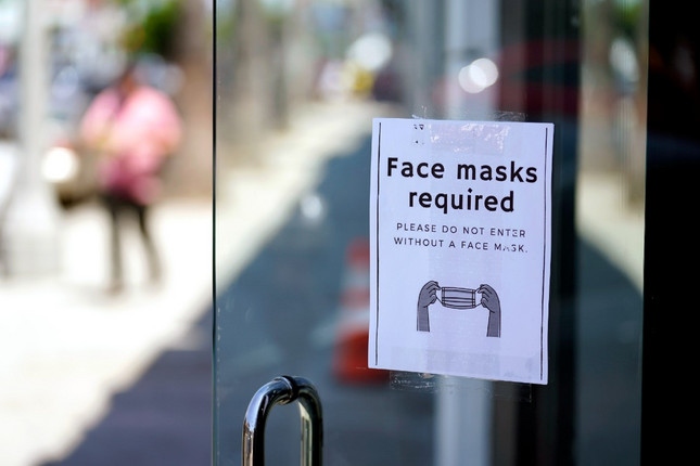 Nightly 7-27-21 photo A sign advises shoppers to wear masks outside of a store in the Fairfax district of Los Angeles.