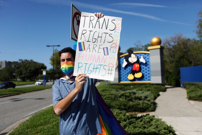 A Disney employee holds a sign while protesting outside of Walt Disney World in Orlando, Fla. 