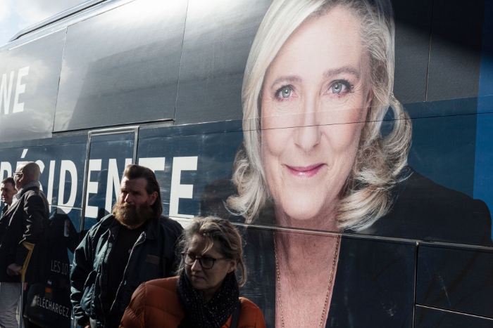 Supporters of presidential candidate Marine La Pen stand in front of one of a fleet of coaches that are used to convey her campaign, in Reims, France.