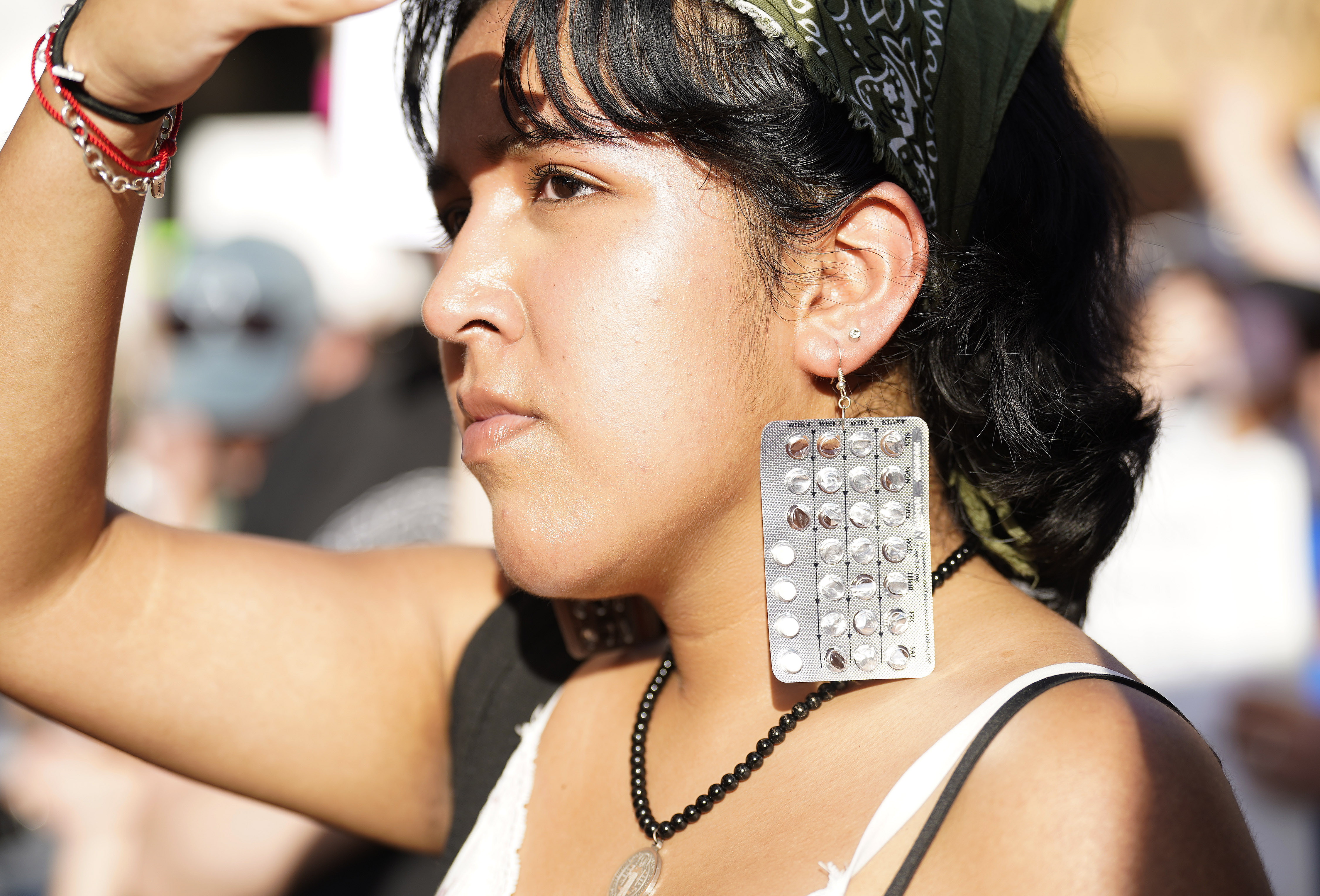 An abortion rights protester wears earings made out of birth control pills.