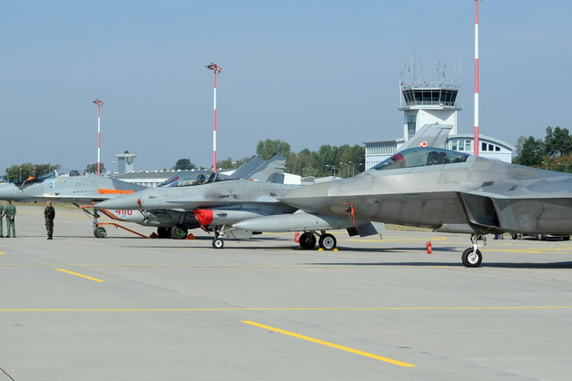 Officials walk past fighter jets parked on the apron.