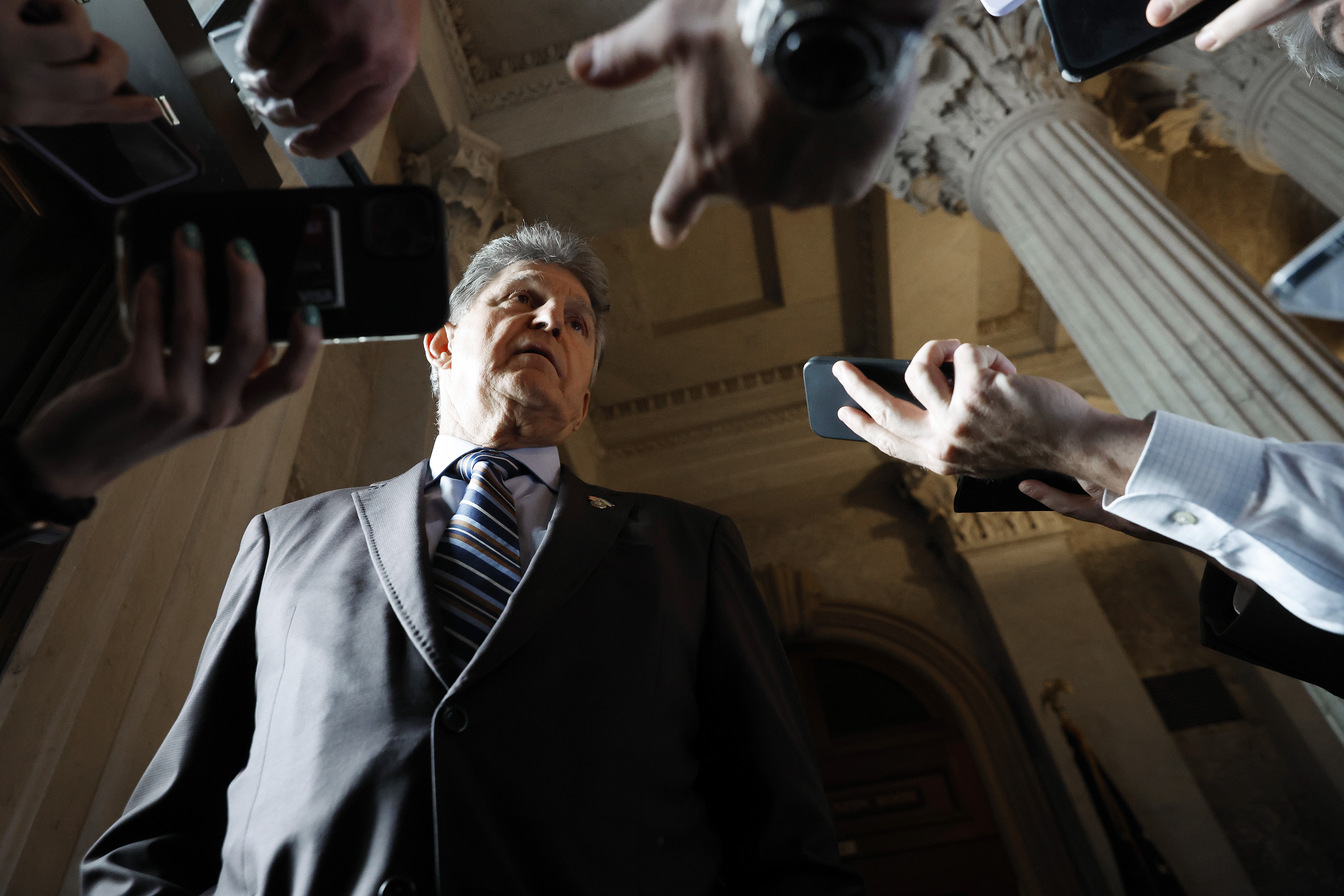 Reporters hold phones up to Manchin to record him.