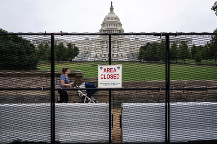Nightly 9-17-21 photo A woman pushes a stroller as she walks inside security fencing surrounding the U.S. Capitol.