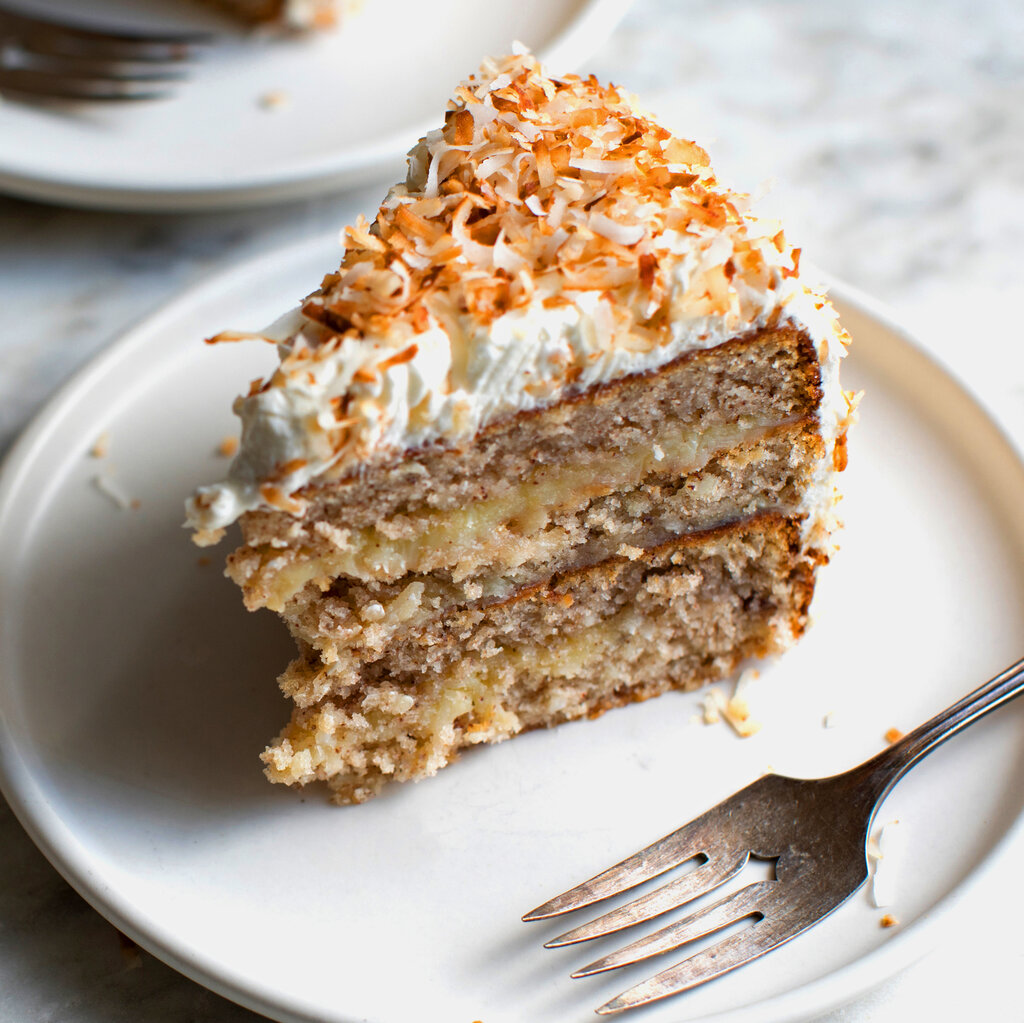 An image of a plate of pecan cake topped with frosting and coconut shavings. 