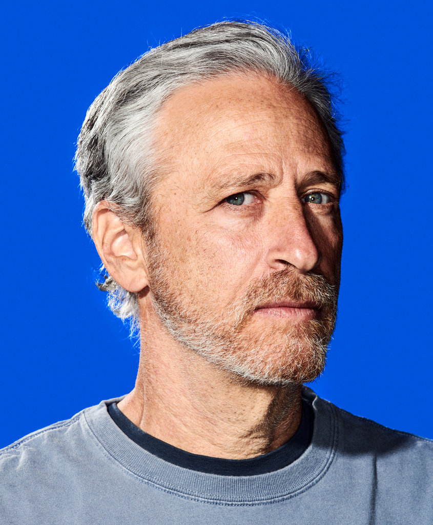A photograph of Jon Stewart against a blue background. 