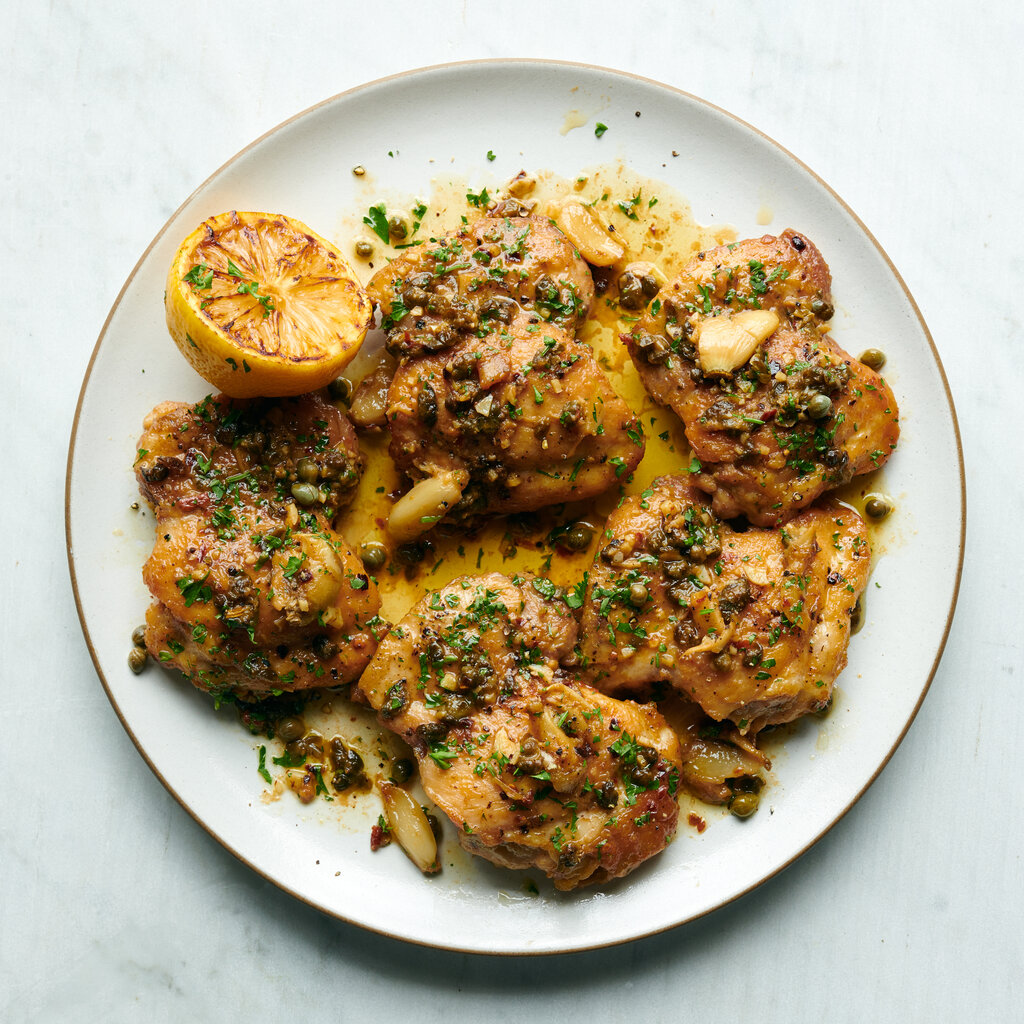 A white plate holds garlicky chicken with lemon-anchovy sauce.