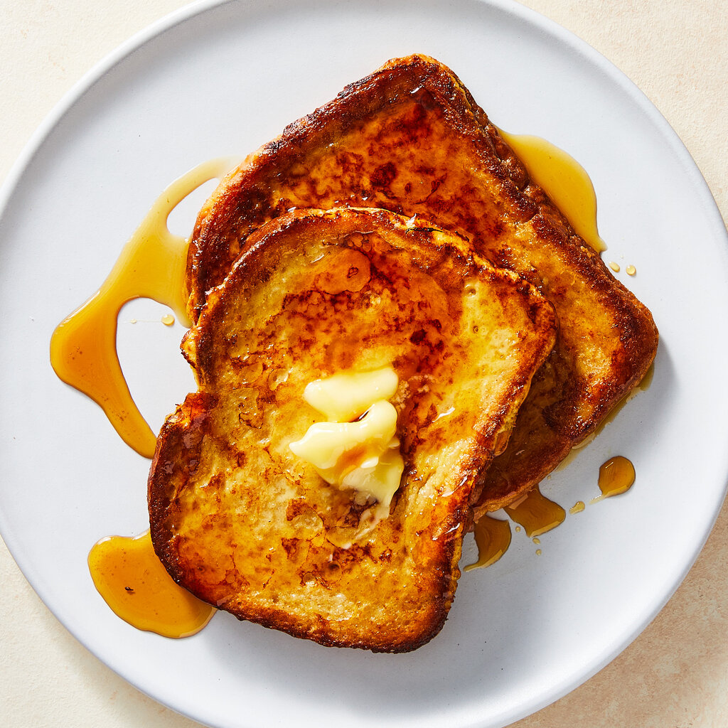 Top down view of toast with butter and syrup on a plate.
