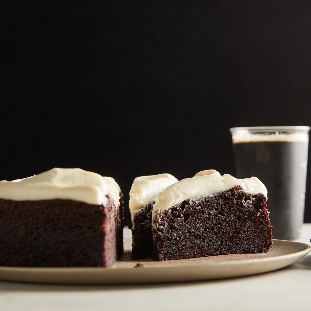 Three slices of chocolate cake beside a glass of Guiness. 