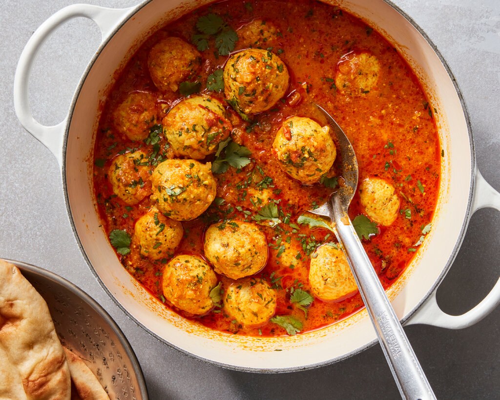 A top-down view of chicken koftas in a tomato sauce. 