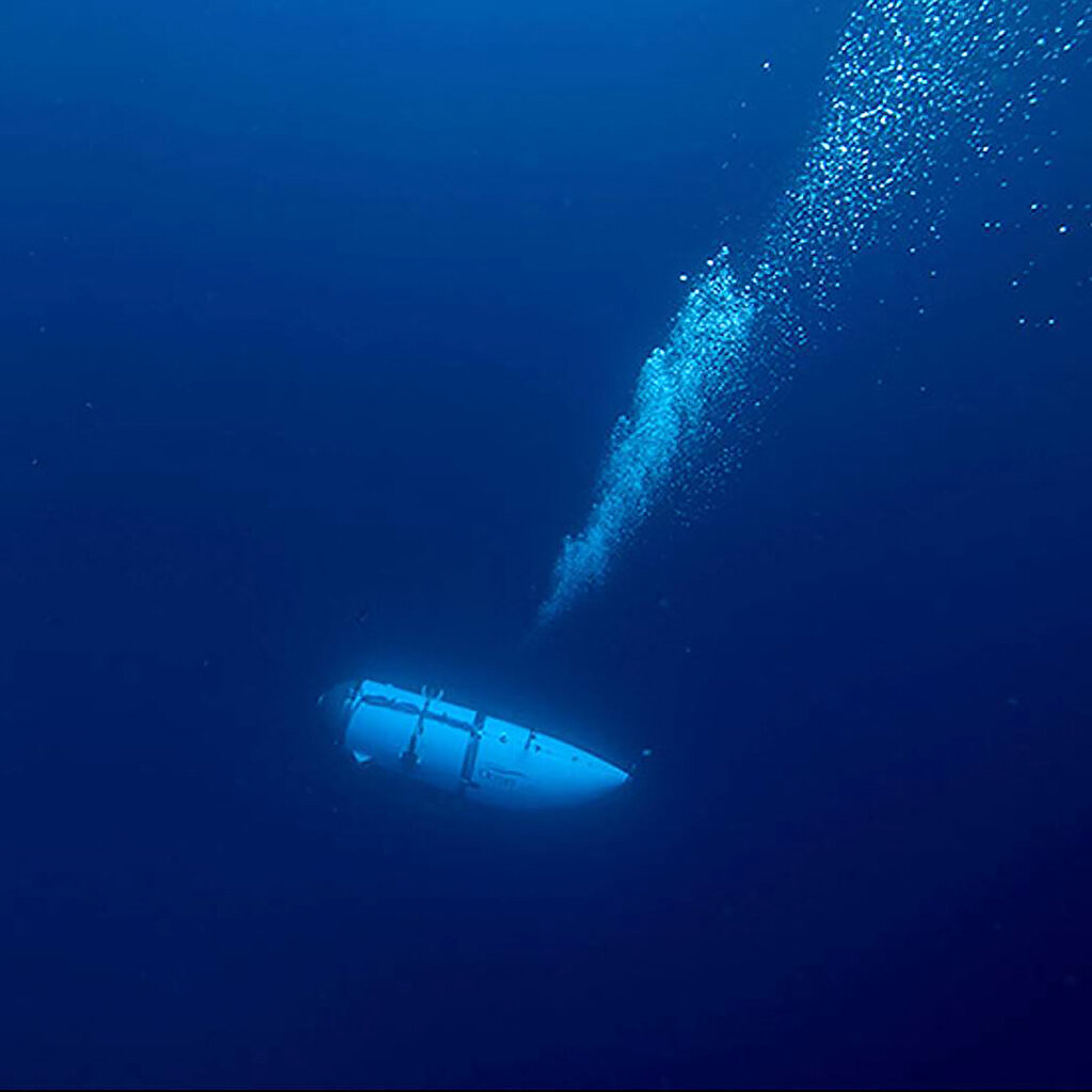 A submersible craft travels through water letting off bubbles.