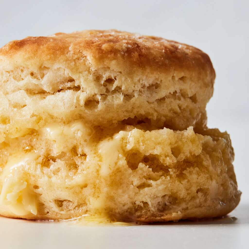 A fluffy, golden biscuit that has been split, filled with melted butter and restacked.