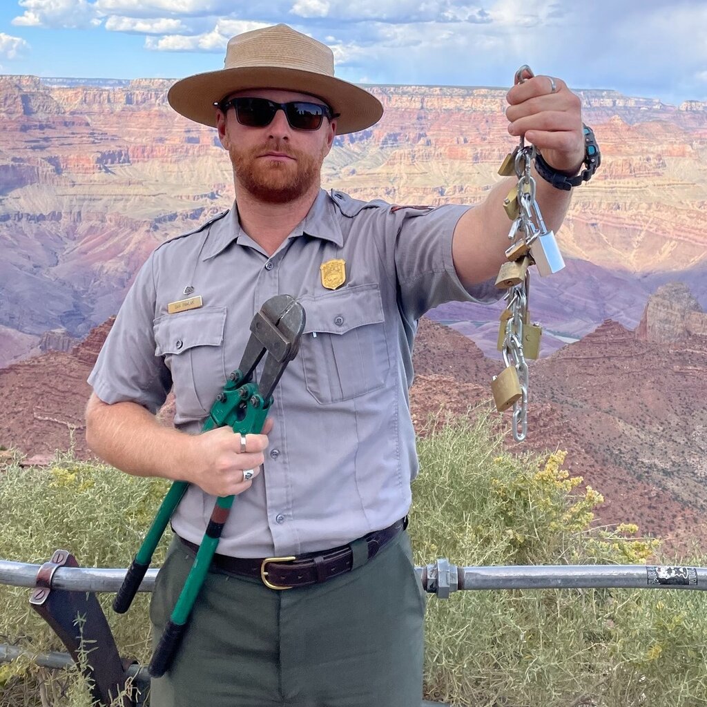A park ranger at the Grand Canyon holds up bolt cutters and a string of locks attached to a chain.