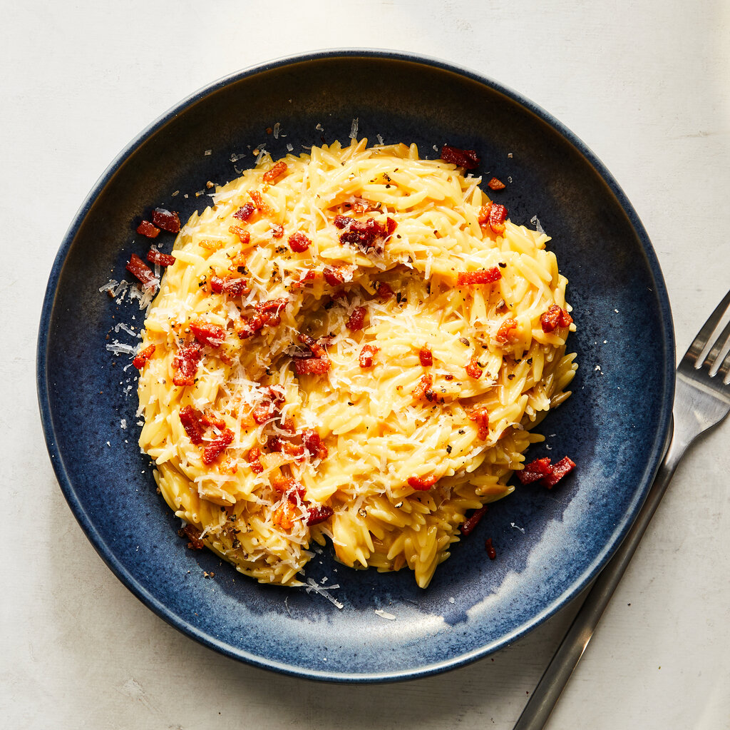 A plate full of pasta with cheese and pancetta. 