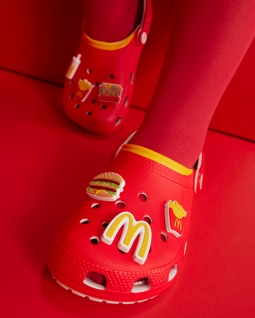 A person’s feet in red tights and red clogs adorned with charms shaped like a Big Mac, a carton of French fries and the golden arches logo.