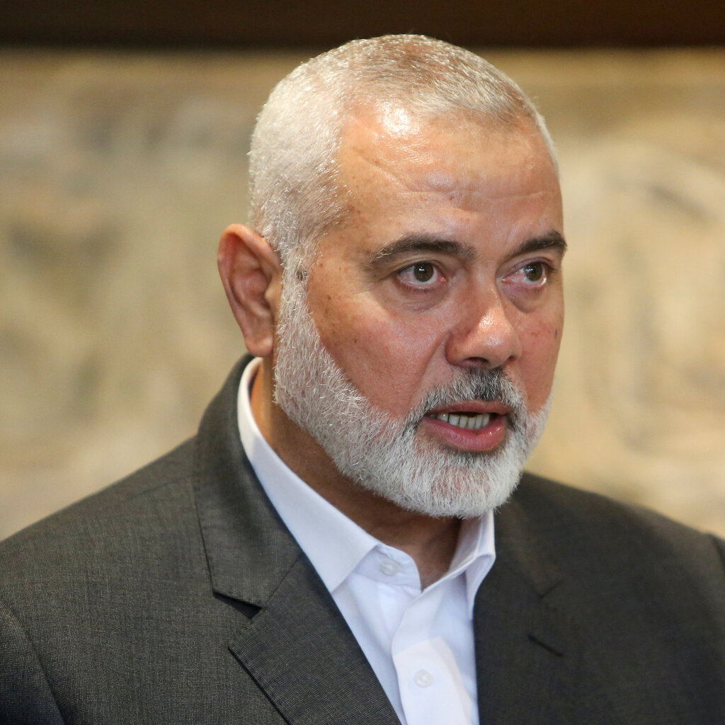 Ismail Haniyeh, with white hair and a white beard, in a suit and white shirt with no tie.