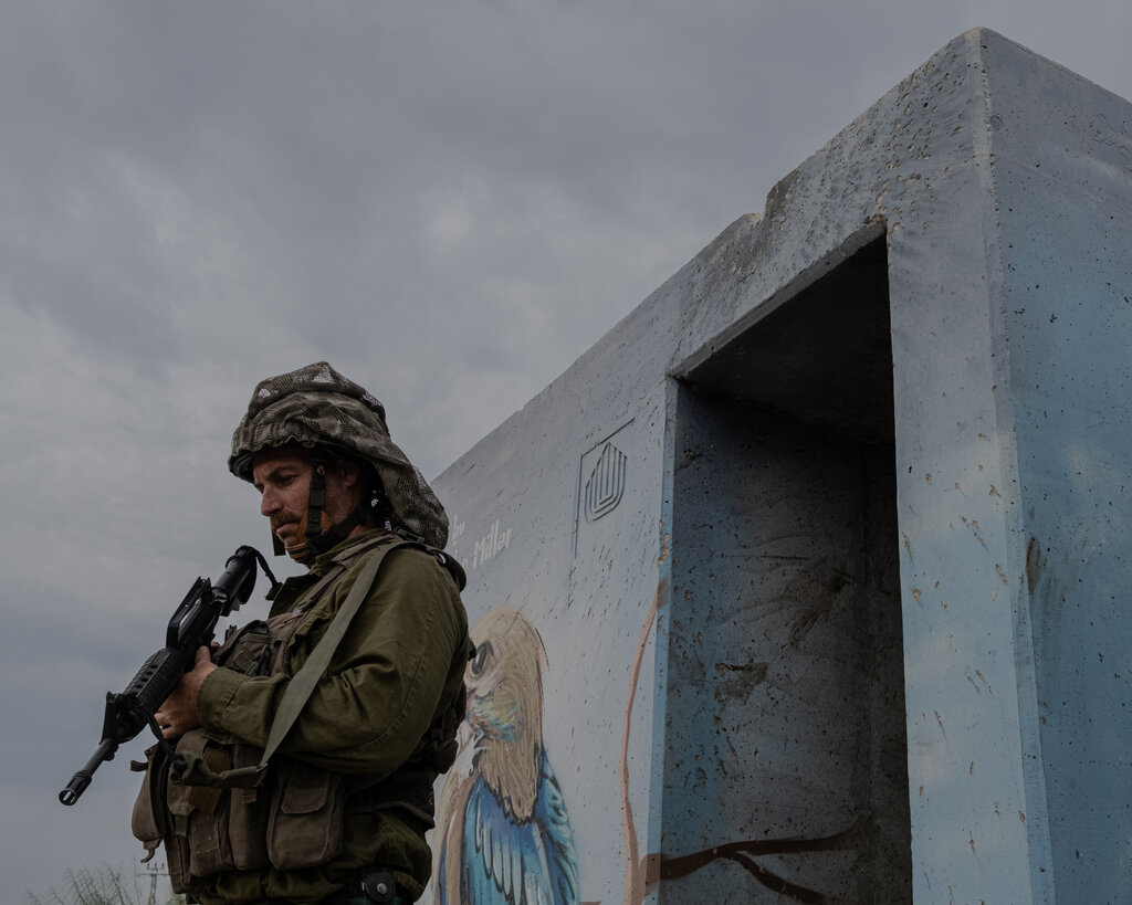 An Israeli soldier holding a gun and standing next to a shelter. 