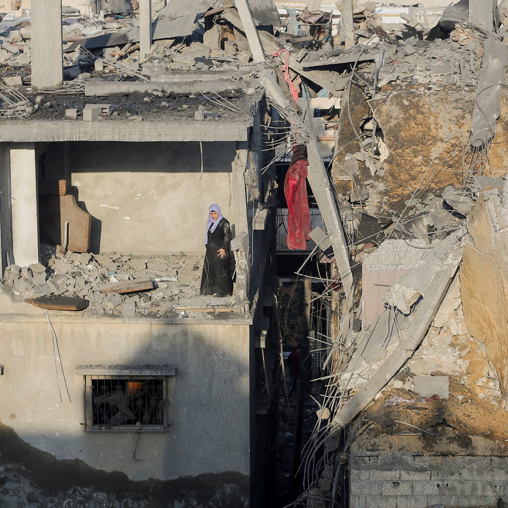 A Palestinian woman stands in a destroyed room in a building as she inspects the site of Israeli strikes.