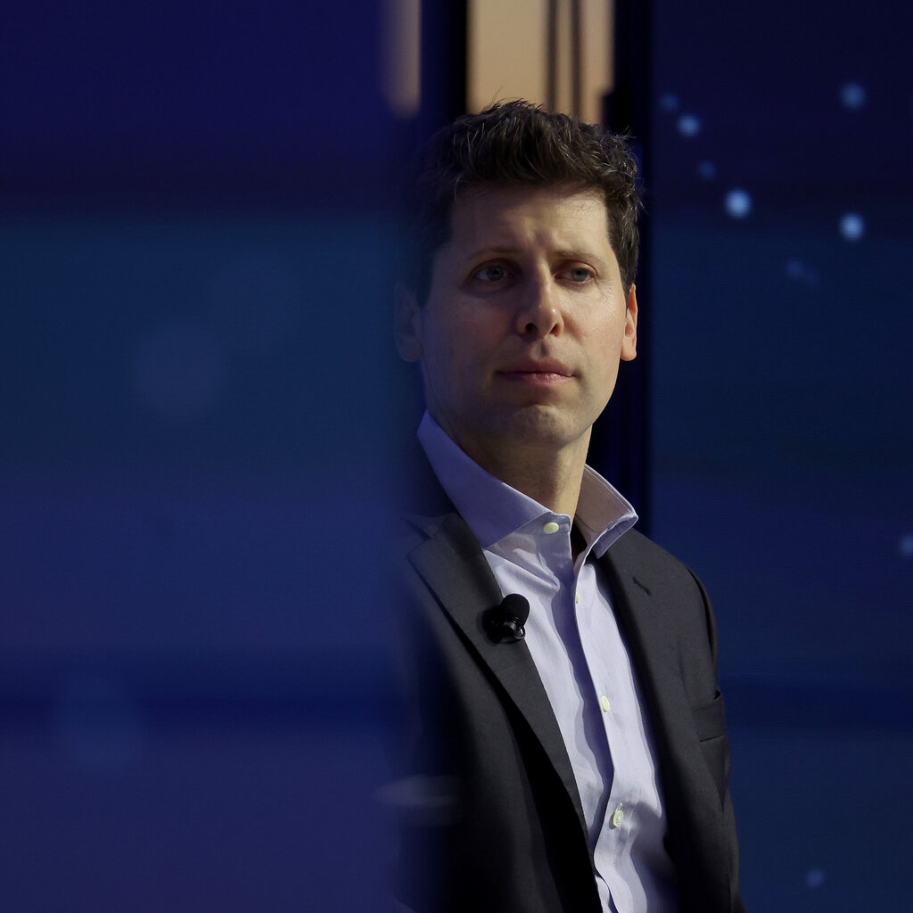 Sam Altman looks off in the distance while wearing a suit without a tie. 