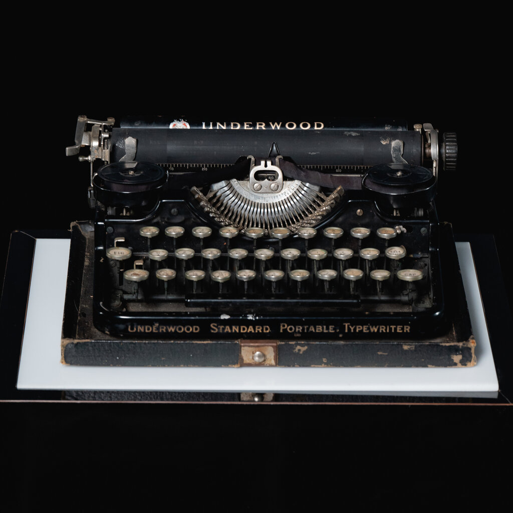 An old black-and-gold typewriter with the words, “Underwood Standard Portable Typewriter” on the front. 