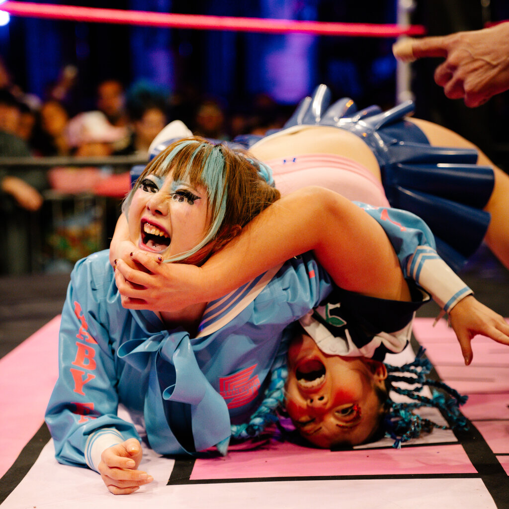 Two female wrestlers with brightly colored hair and clothing.