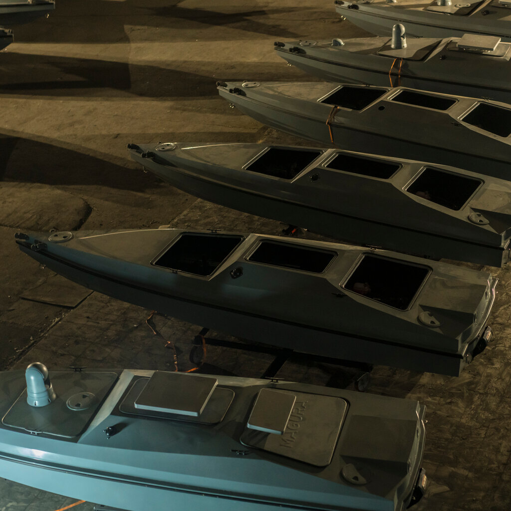 Sea drones — small speedboat hulls with an upper body containing three openings — in a workshop. 