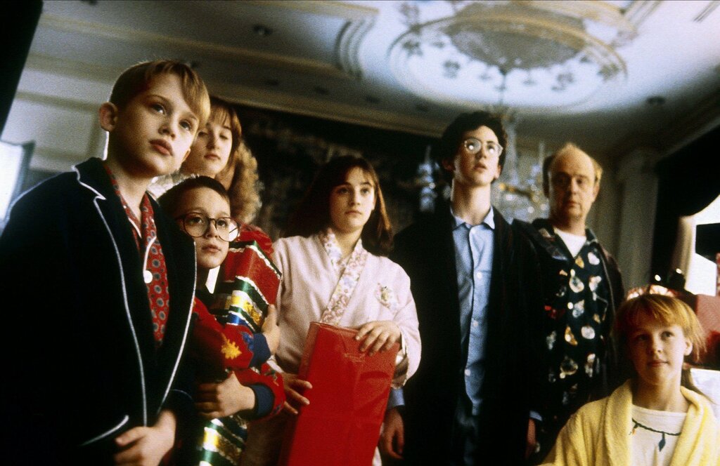 A scene from the film “Home Alone,” with several children in a large living room staring at something out of frame.
