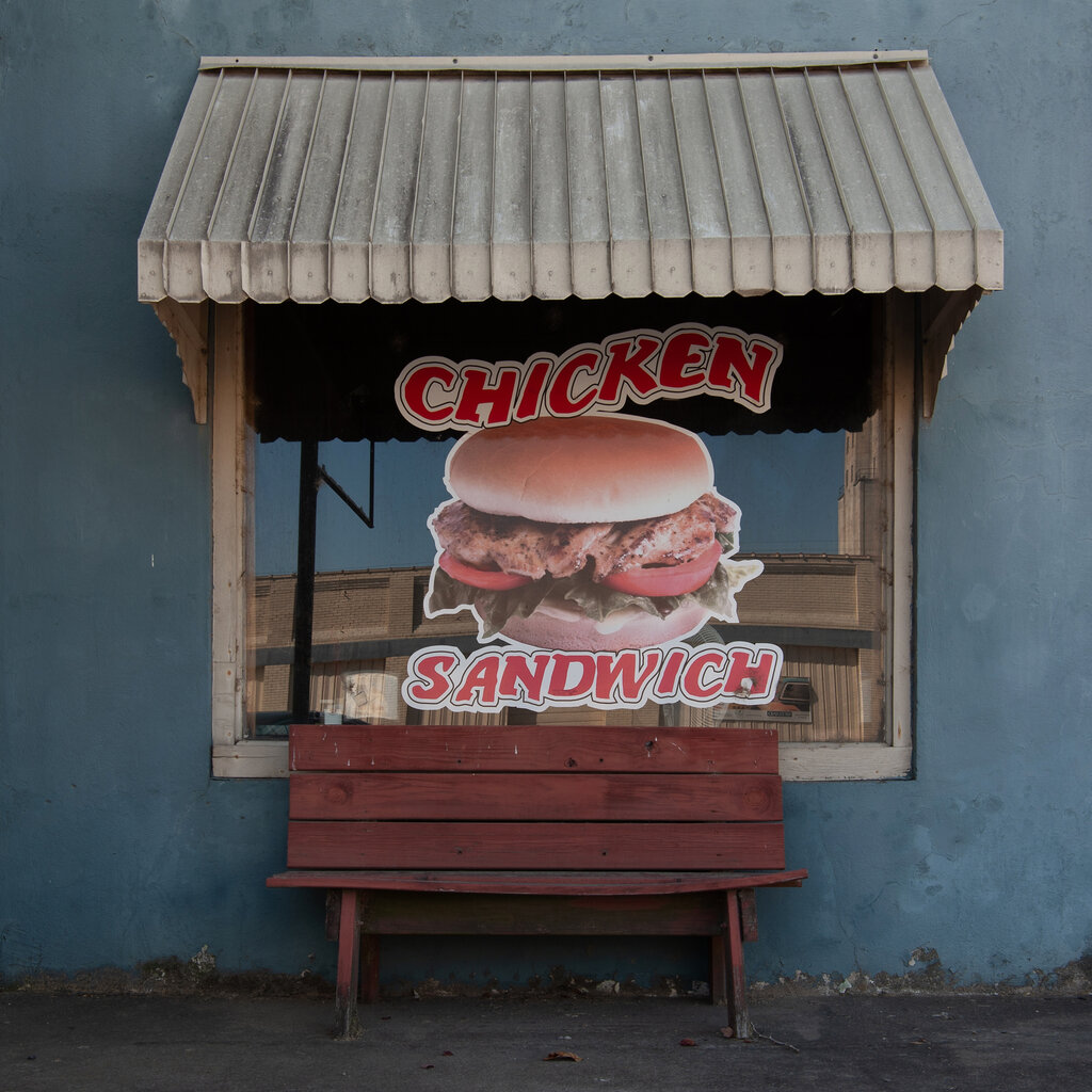 A window of a store, advertising a chicken sandwich. 