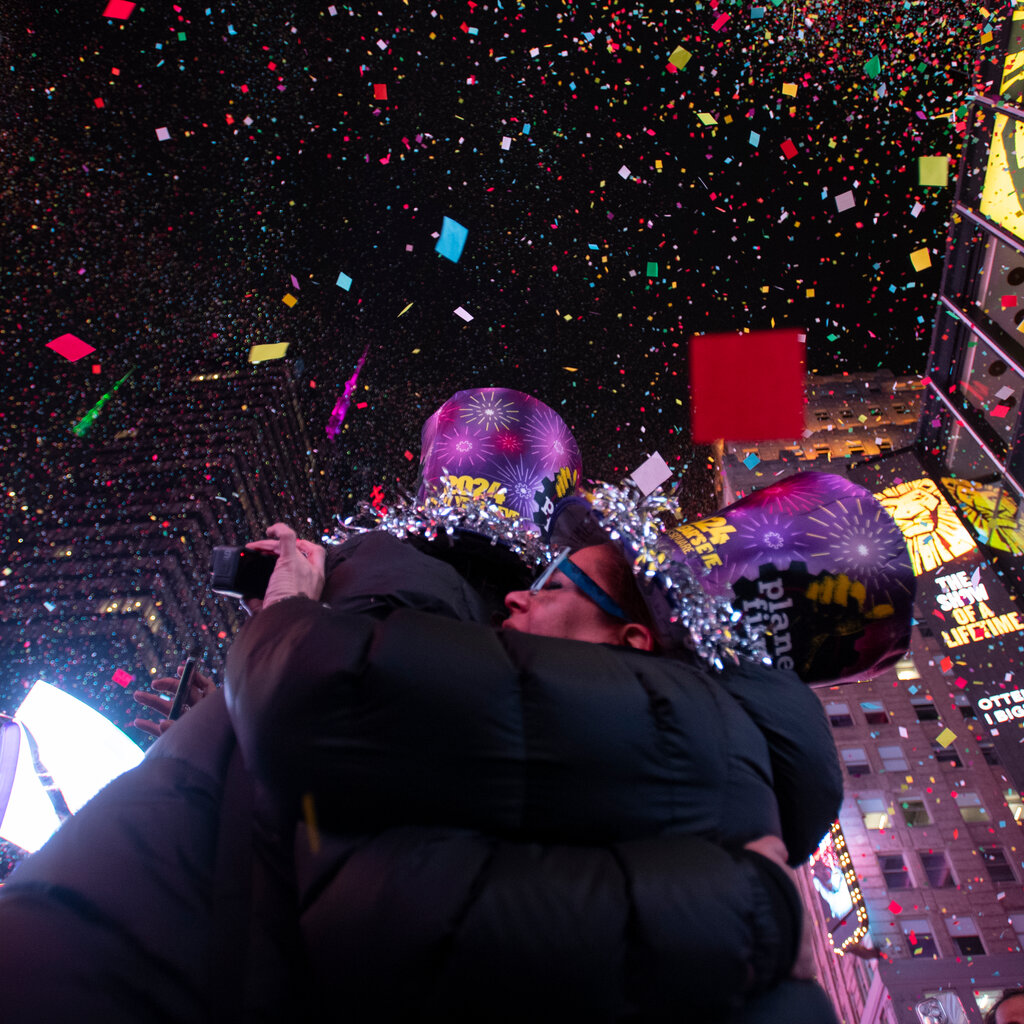 Two revelers hug in Times Square as confetti fills the sky.