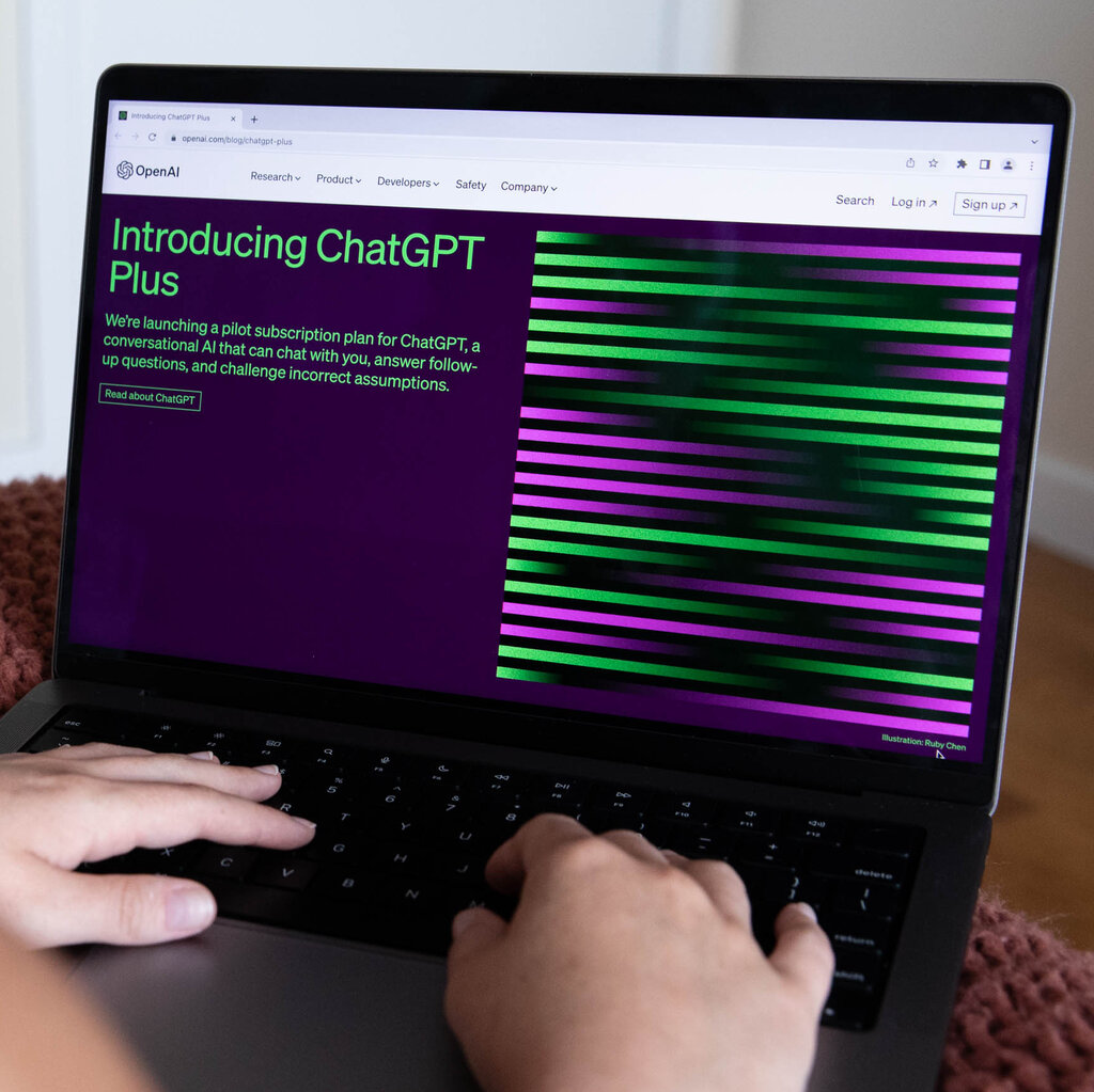 A computer screen with the words "Introducing ChatGPT Plus" and a person's hand on the keyboard.